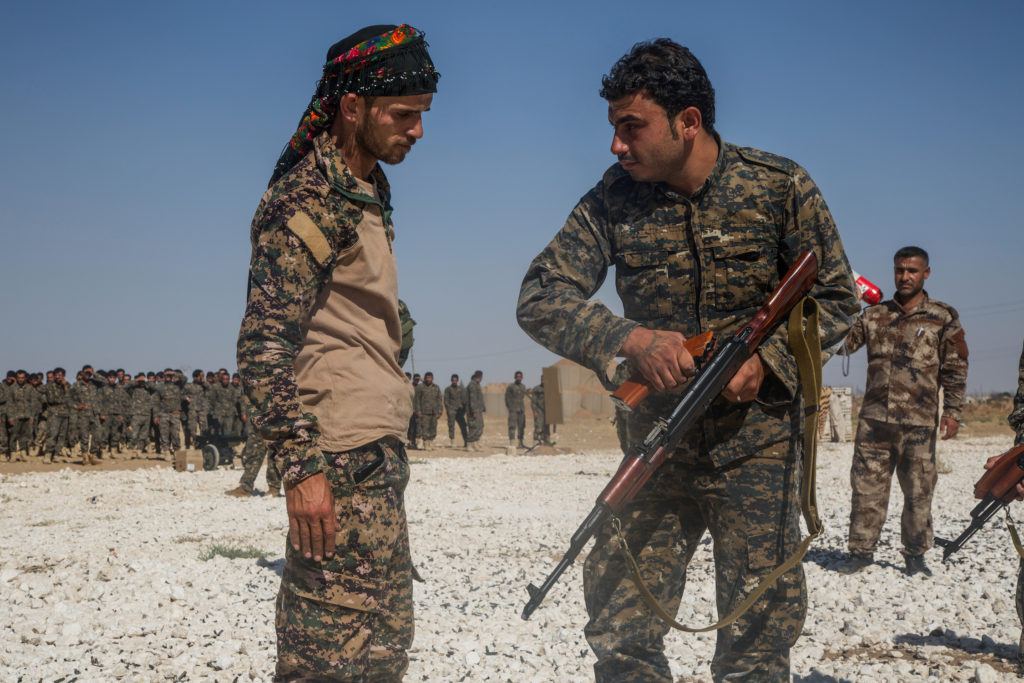An instructor with the Syrian Democratic Forces observes a Syrian Arab trainee clear his rifle during small arms training in Northern Syria,