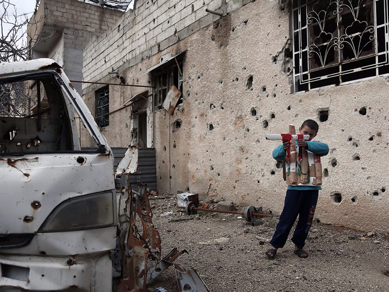 A Syrian child plays with a cardboard gun in Eastern Ghouta