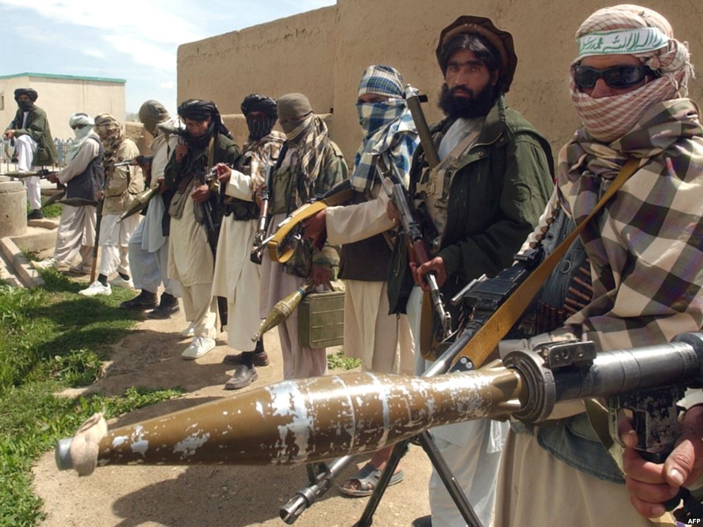 Taliban militants in a line holding guns and explosives
