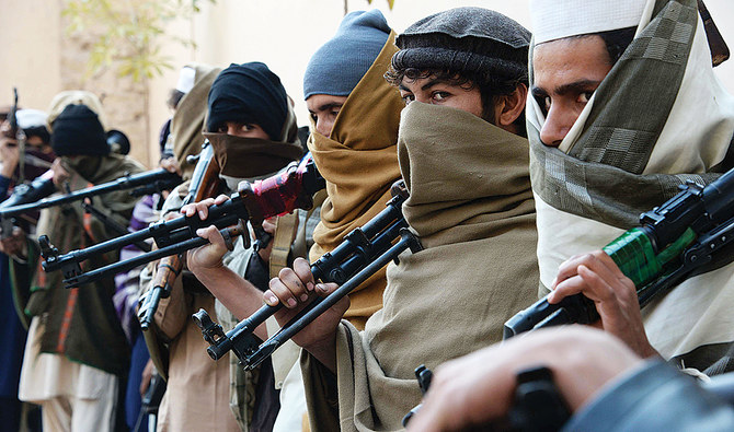 Taliban fighters holding weapons stand in a queue