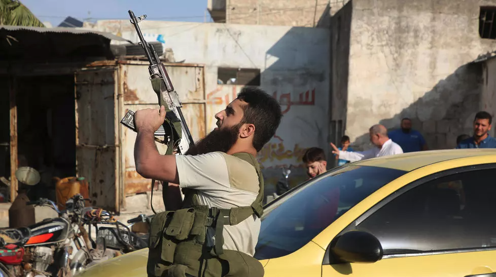 A fighter with the Turkey-backed Faylaq al-Sham rebel faction in Syria shoots in the air during the funeral of 10 of the faction's fighters killed in a Russian air strike