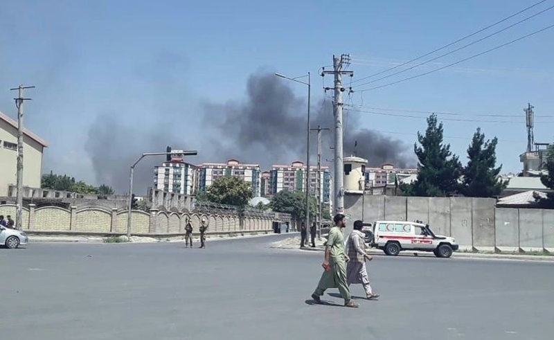 Afghan men walk on a road as smoke rises from the site of an attack in Kabul on 1 July 2019.