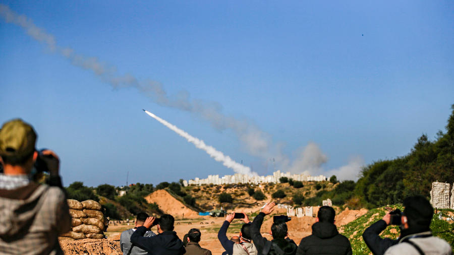 People watch as rockets are fired into the sea during a military drill in Gaza to mark the anniversary of the start of the 2008 conflict with Israel