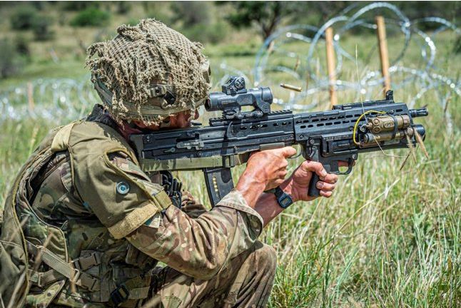 A British soldier fires his SA80-A3 with underslung grenade launcher during a live firing platoon level attack Exercise in Kenya.
