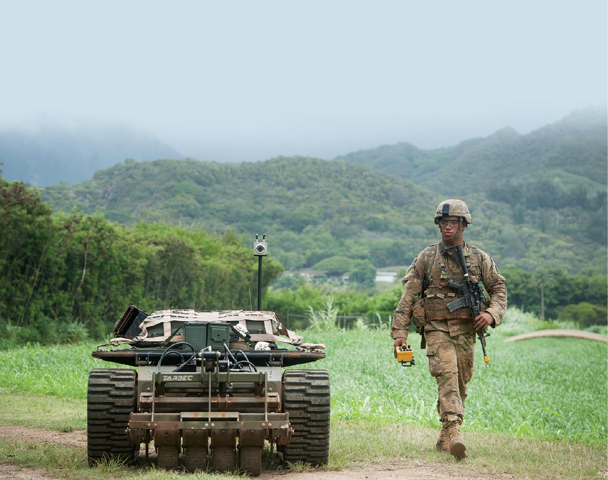 A US Army Pacific soldier walks down a trail 22 July 2016 while controlling an unmanned vehicle as part of the Pacific Manned Unmanned–Initiative at Marine Corps Training Area Bellows, Hawaii.