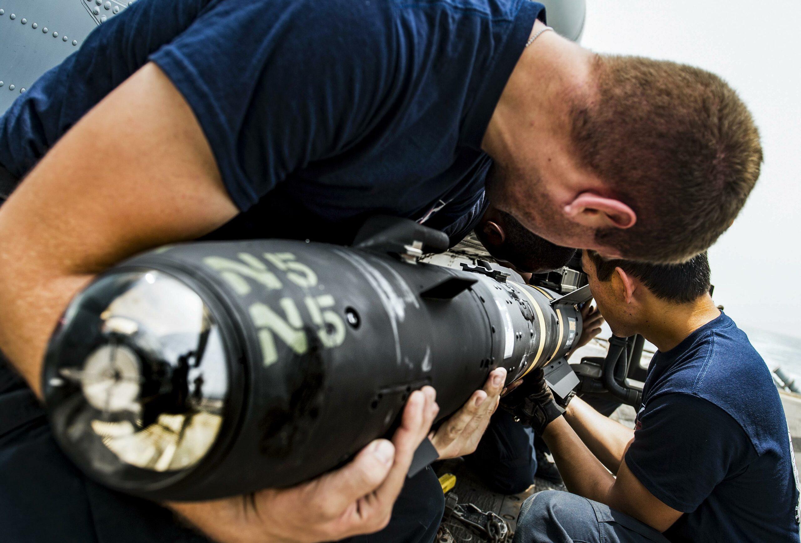 Sailors load an AGM-114 Hellfire missile onto an MH-60R Seahawk helicopter
