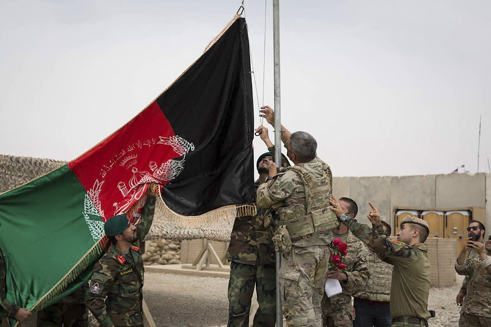 This handout photograph taken on May 2, 2021 and released by Afghanistan's Ministry of Defense shows US soldiwrs and Afghan National Army (ANA) soldiers rising Afghanistan's national flag uring a handover ceremony to the Afghan National Army (ANA) army 215 Maiwand corps at Antonik camp in Helmand province.
