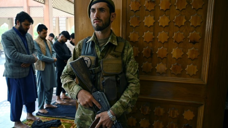 An Afghan soldier stands guard as Muslim devotees offer prayers to start the Eid-al-Fitr festival marking the end of the Islamic holy fasting month of Ramadan during a three-day ceasefire agreed by the warring Taliban and Afghan forces, at the Abdul Rahman Mosque in Kabul on May 13, 2021.