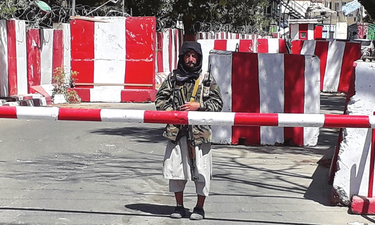 A Taliban fighter stands guard at the entrance of the police headquarters in Ghazni on August 12, 2021