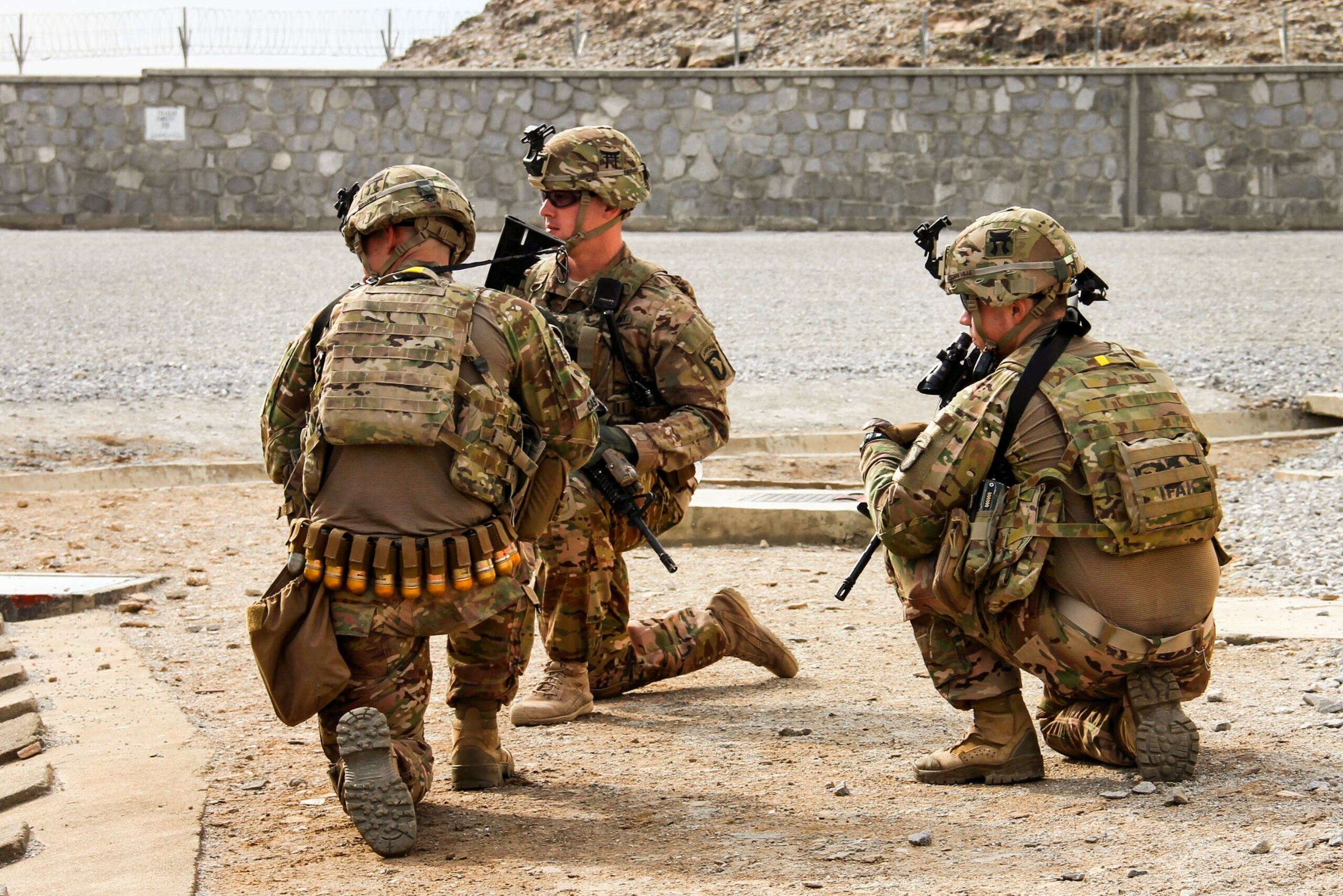 Three soldiers from the 3rd Brigade Combat Team, 101st Airborne Division (Air Assault), assigned to the Train, Advise, Assist Command - East security force, hold their positions and prepare for the landing of a UH-60 Black Hawk helicopter