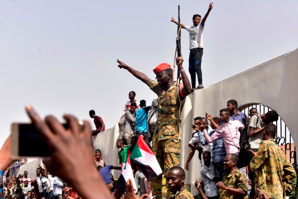 After Sudanese President Omar al-Bashir was ousted, members of the Sudanese military gather in a street with protestors in central Khartoum