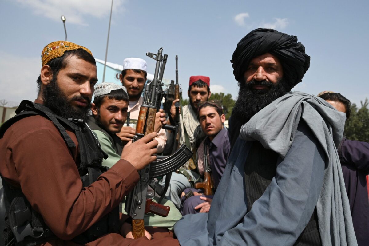 Taliban fighters sit on the back of a pick-up truck at the airport in Kabul