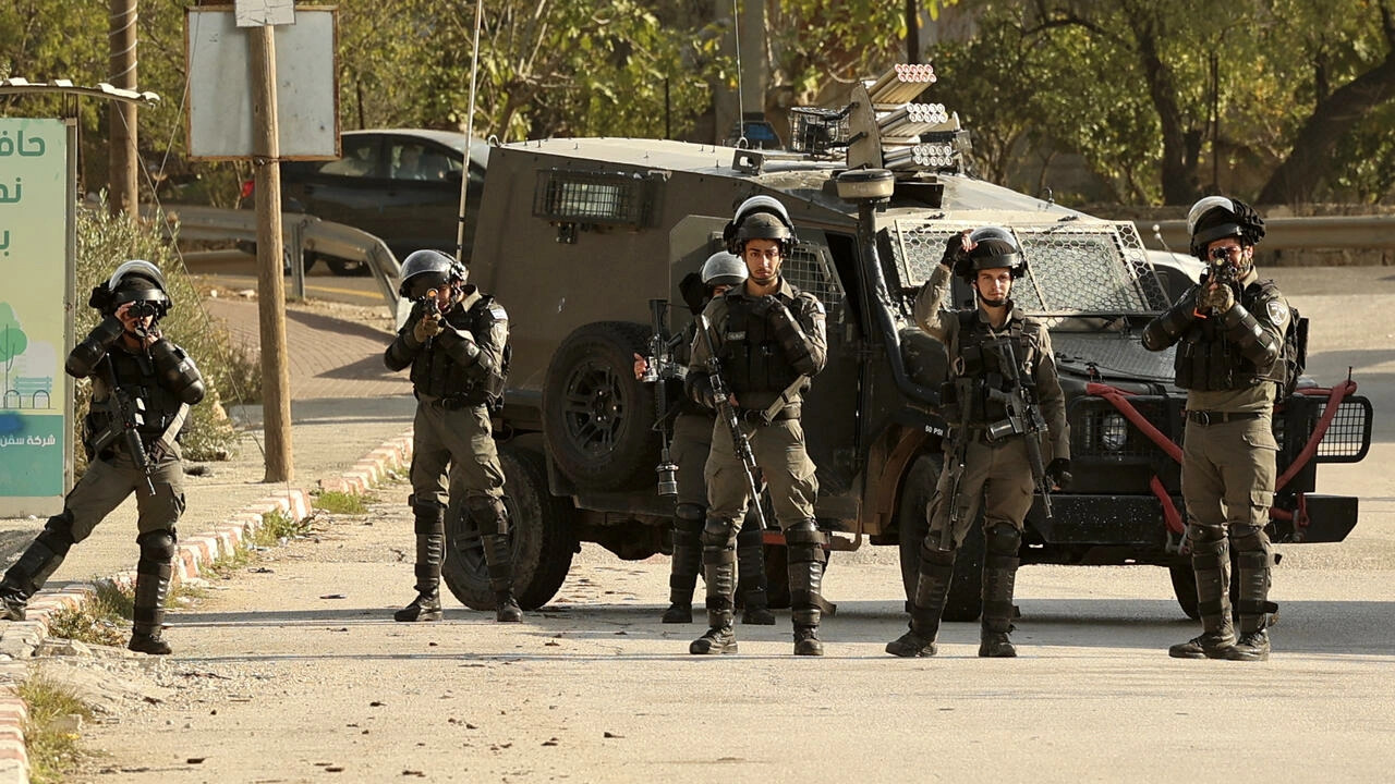 Members of the Israeli border guards block the entrance to the village of Al-Lubban Al-Sharqiah, south of Nablus, during a demonstration by settlers at the entrance to the village