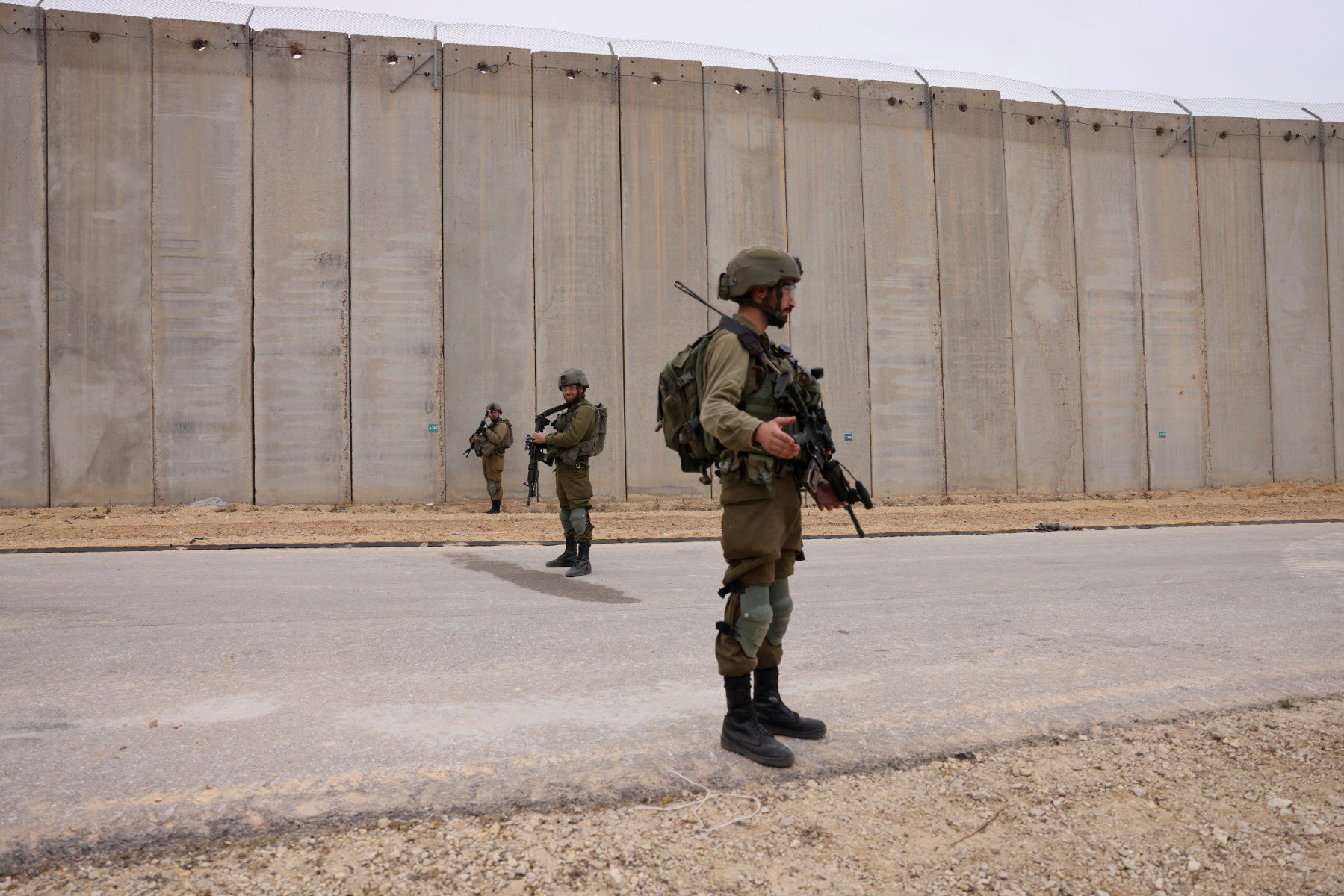 Israeli soldiers stand on guard by the fence along the border with the Gaza Strip