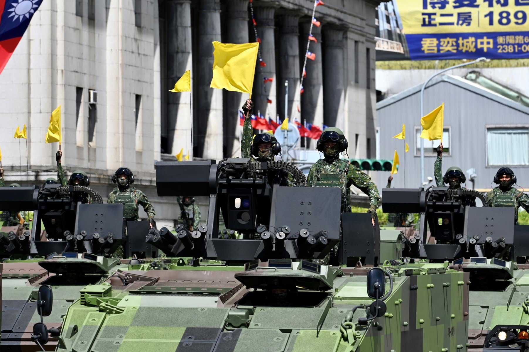 Taiwanese soldiers raise flags on military vehicles during a national day parade