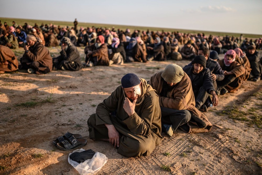 Men suspected of being Islamic State fighters wait to be searched by members