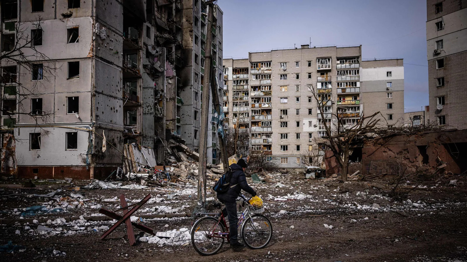 A man rides his bicycle in front of residential buildings damaged in yesterday's shelling in the city of Chernihiv