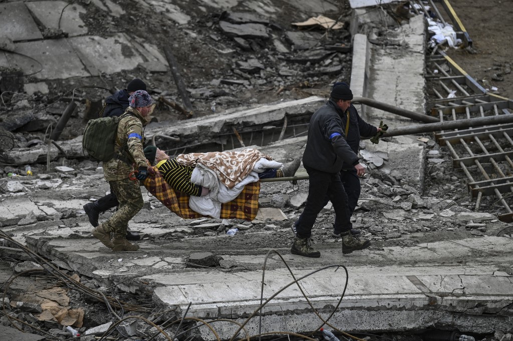 Ukrainian servicemen evacuate an elderly woman