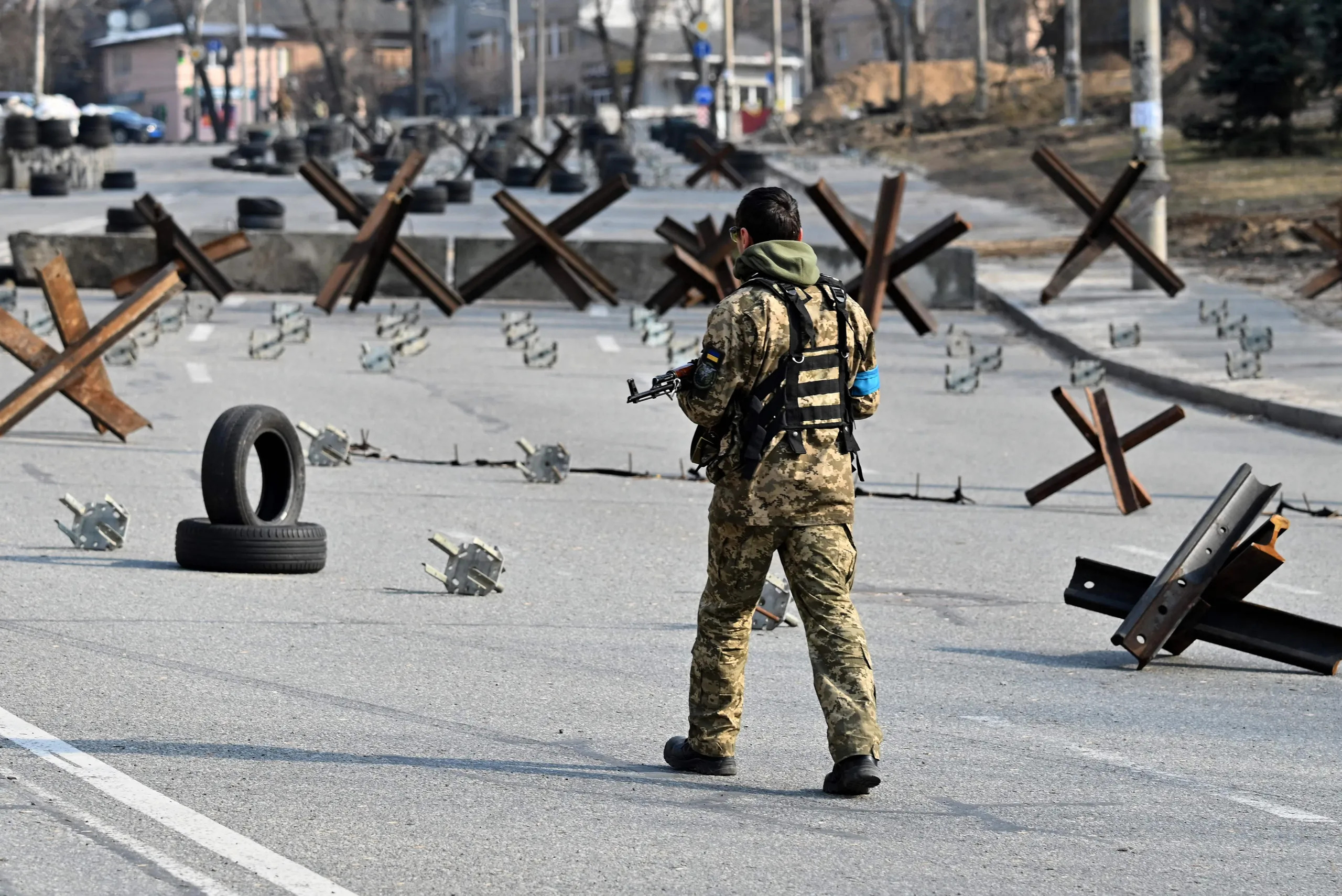 A Ukrainian soldier passes by anti-tank protection elements as he stands guard at a checkpoint