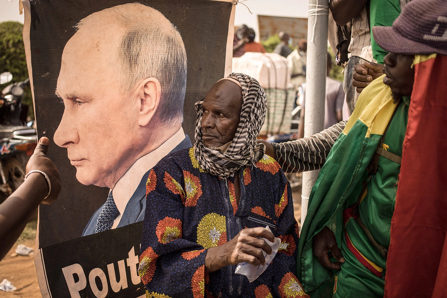 A man sits near a portrait of Russian President Vladimir Putin during a demonstration in Bamako, Mali