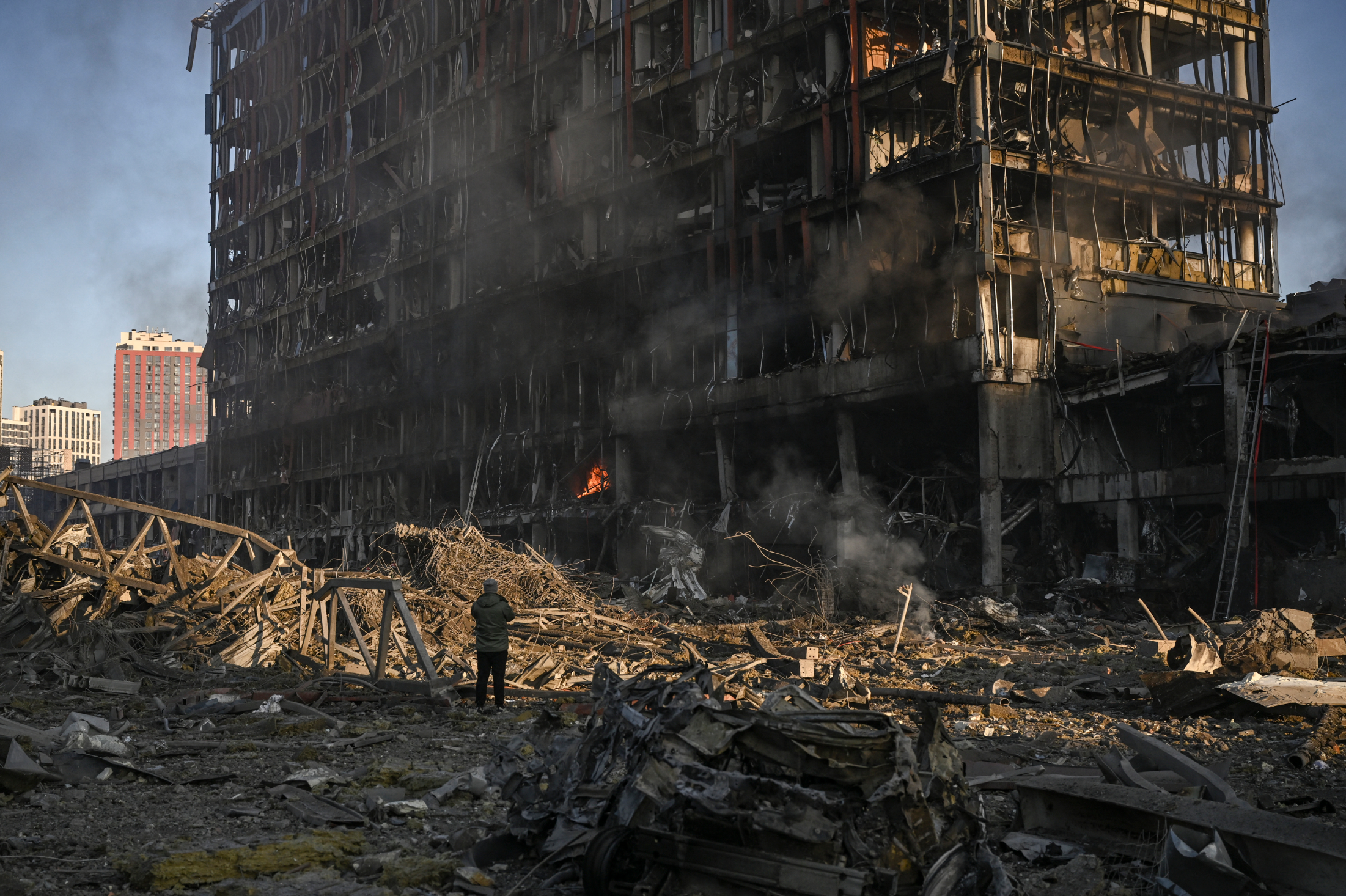 A man stands looking at the burning and destroyed Retroville shopping mall