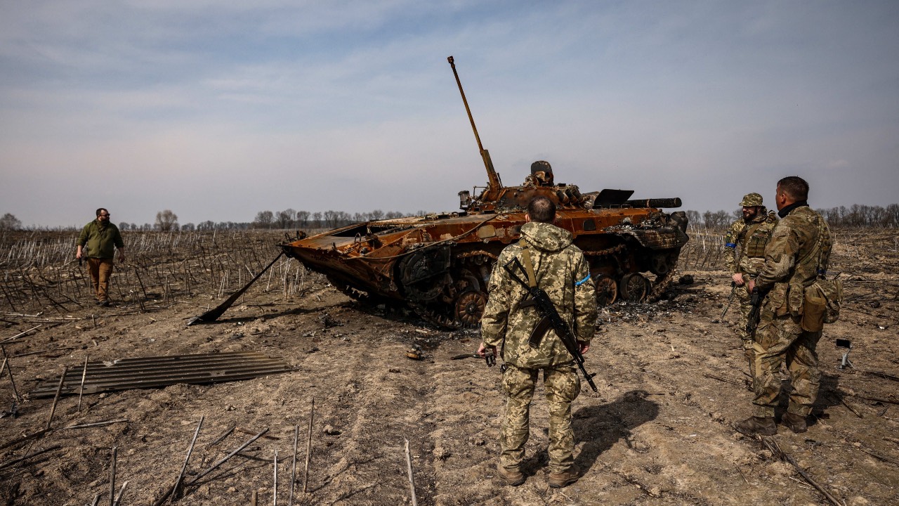Ukrainian soldiers stand by a burnt Russian tank on the outskirts of Kyiv, on 31 March, 2022