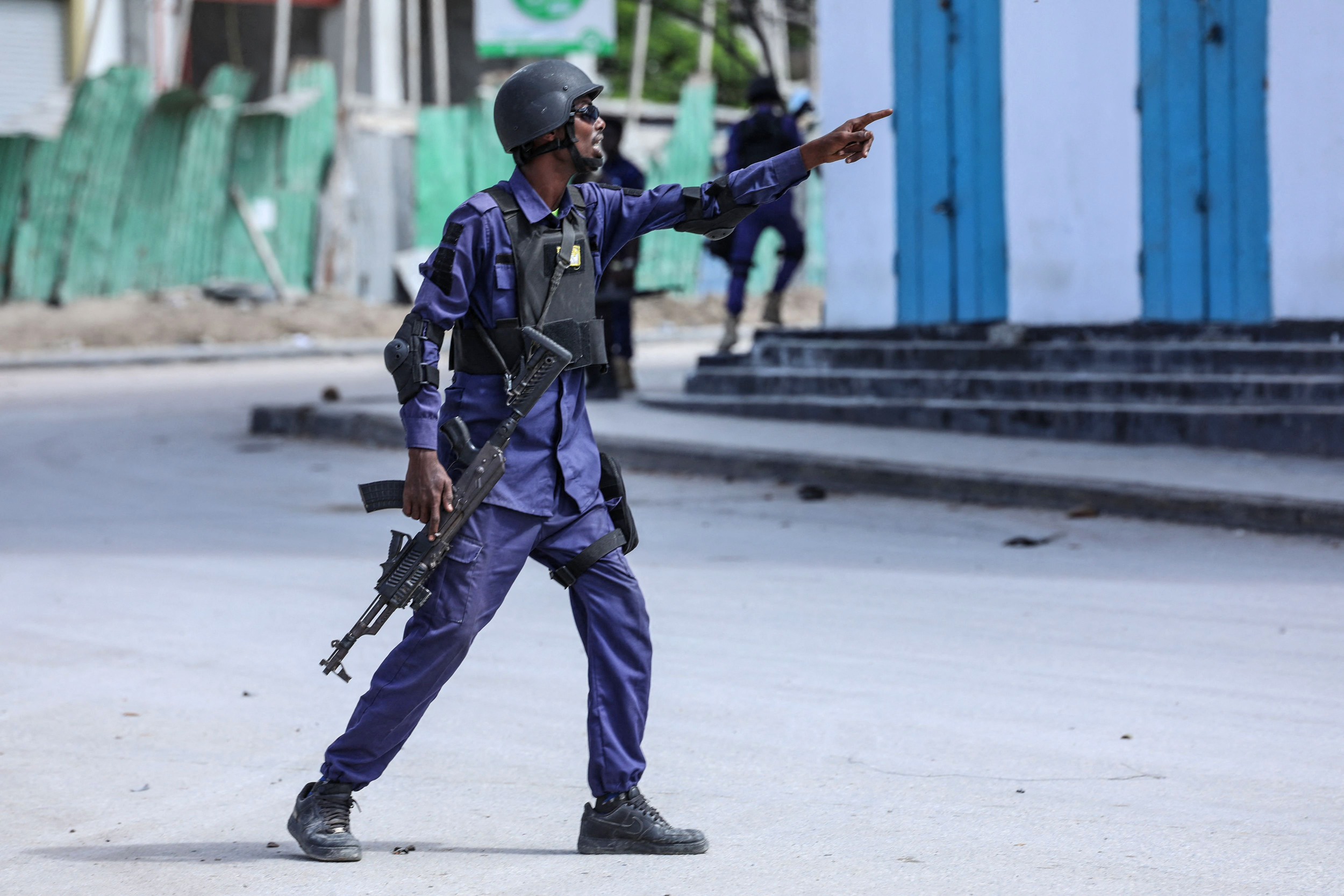 A security officer gestures as he and colleagues patrol at the the site of explosions in Mogadishu