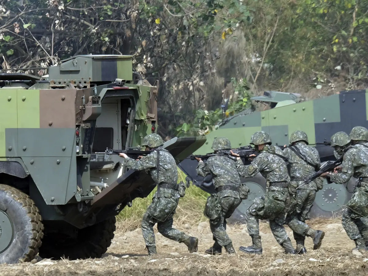 Taiwan soldiers walk behind an armored personnel carrier during an annual military drill in Taichung, central Taiwan