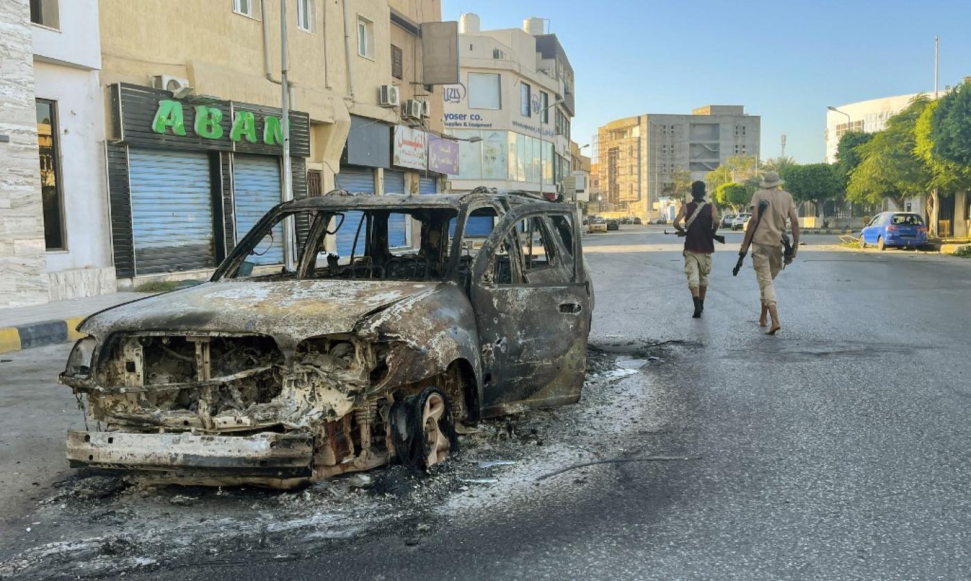 A damaged vehicle is pictured in a street in the Libyan capital Tripoli following clashes between rival local groups