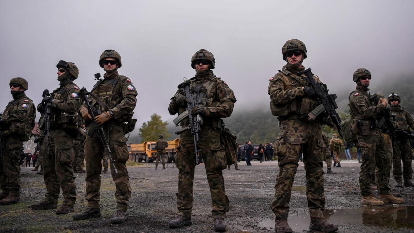 NATO soldiers serving in Kosovo patrol next to a road barricade set up by ethnic Serbs near the town of Zubin Potok