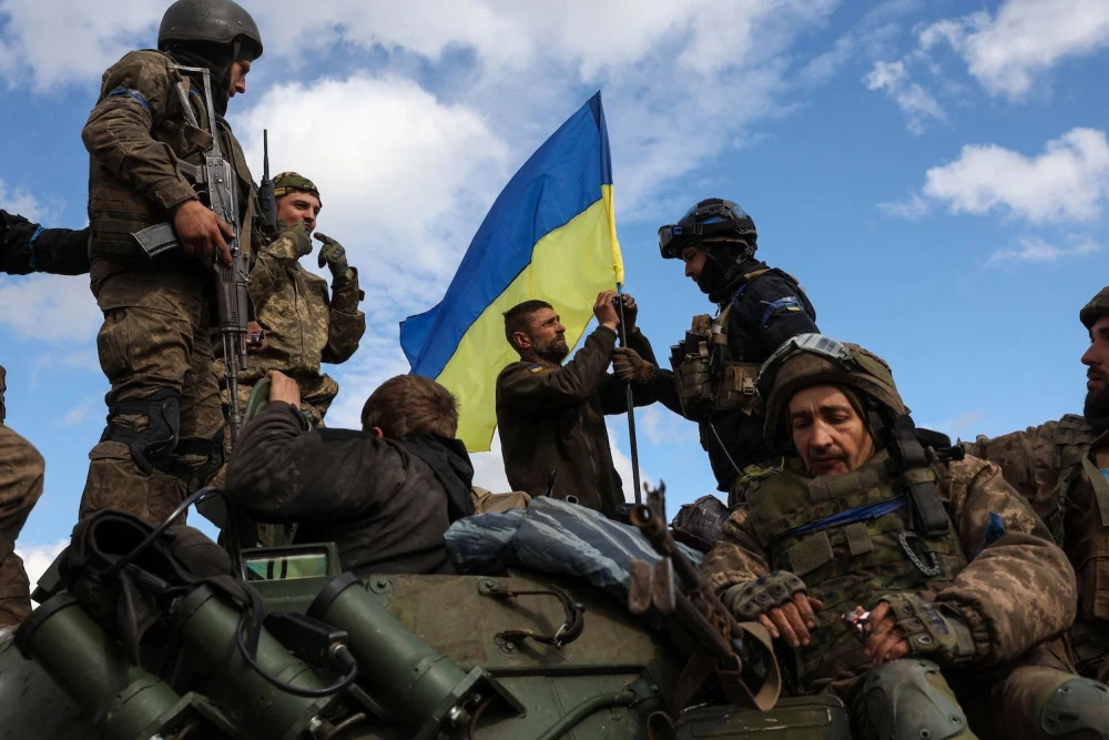 Ukrainian soldiers adjust a national flag atop a personnel armored carrier on a road near Lyman in the Donetsk region on Oct. 4, amid the Russian invasion of Ukraine