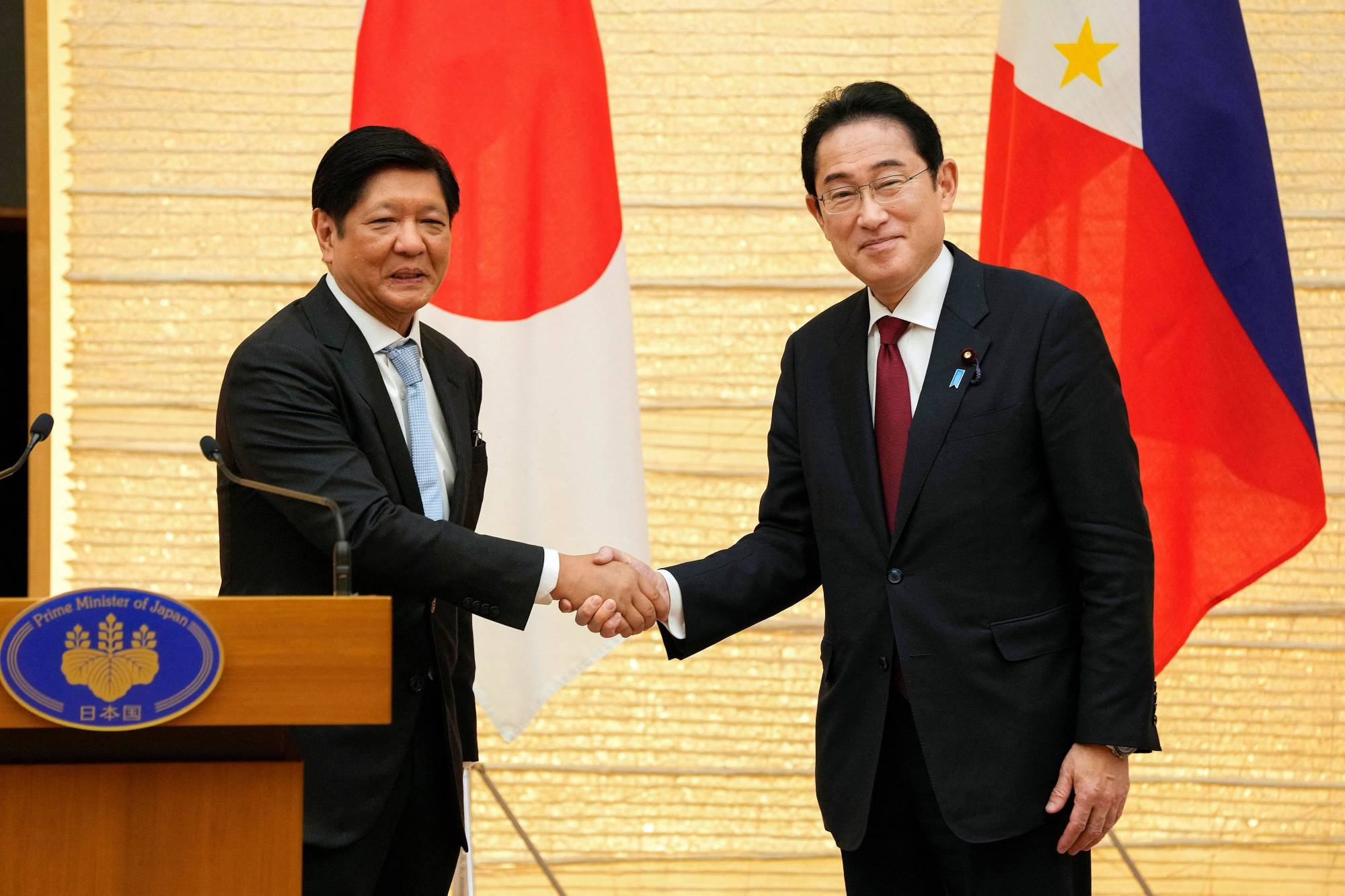 Japanese Prime Minister Fumio Kishida shakes hands with Philippine President Ferdinand Marcos during a press conference