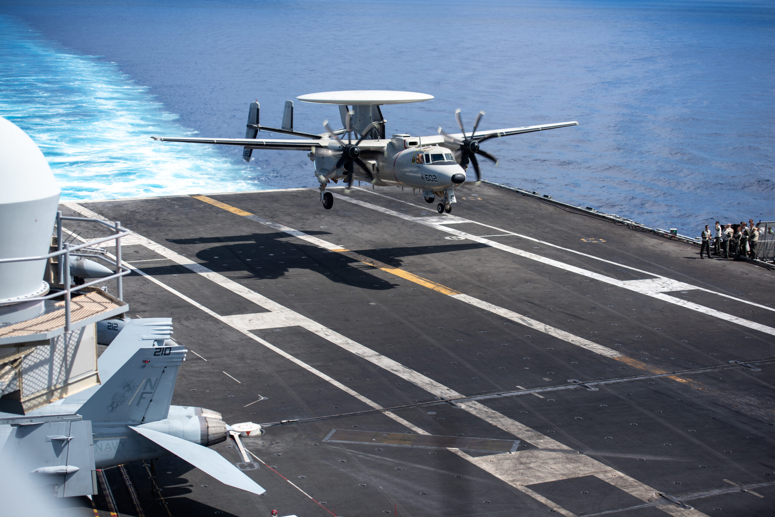 220810-N-WU964-1044 PHILIPPINE SEA (Aug. 10, 2022) Cmdr. Edmund Poynton, commanding officer of the Tigertails of Airborne Early Warning Squadron (VAW) 125 lands on the flight deck of the U.S. Navy’s only forward-deployed aircraft carrier USS Ronald Reagan (CVN 76) in an E-2D Hawkeye after a change of command ceremony, in the Philippine Sea, Aug. 10. During the change of command ceremony Cmdr. David Wiltshire transferred command of VAW 125 to Poynton. Ronald Reagan, the flagship of Carrier Strike Group 5, provides a combat-ready force that protects and defends the United States, and supports alliances, partnerships and collective maritime interests in the Indo-Pacific region. (U.S. Navy photo by Mass Communication Specialist 3rd Class Dallas A. Snider)