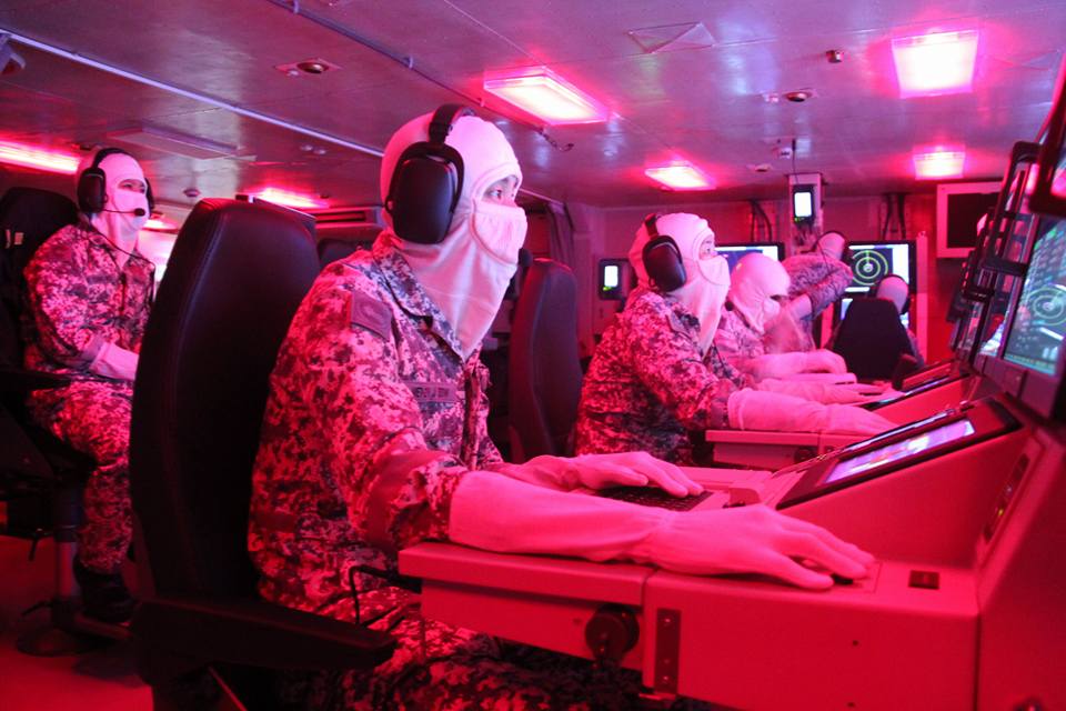 Singaporean armed forces in ship control room at sea.