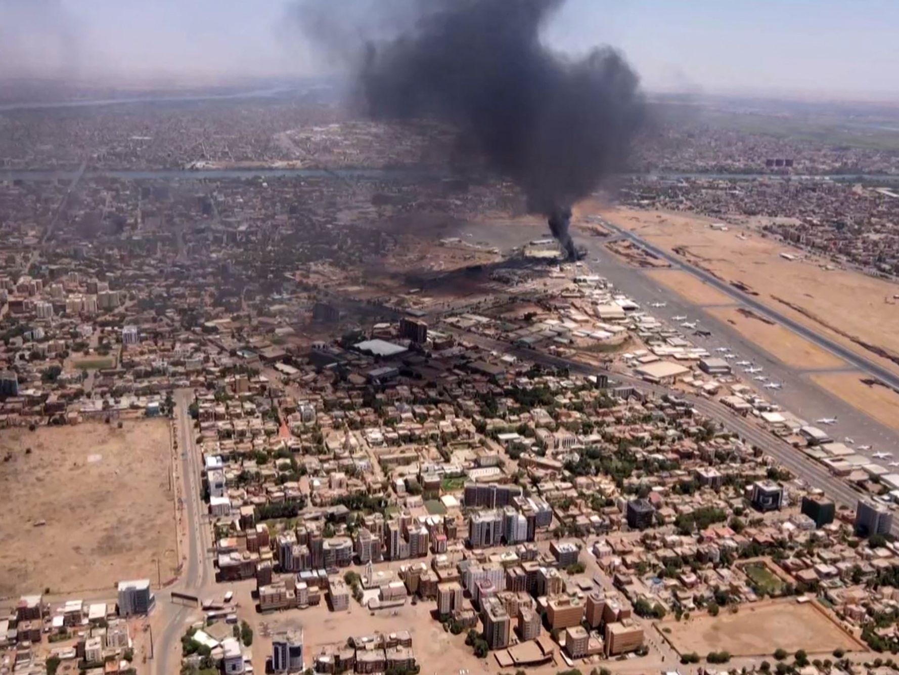 An aerial view shows black smoke rising above the Khartoum International Airport in Khartoum, Sudan