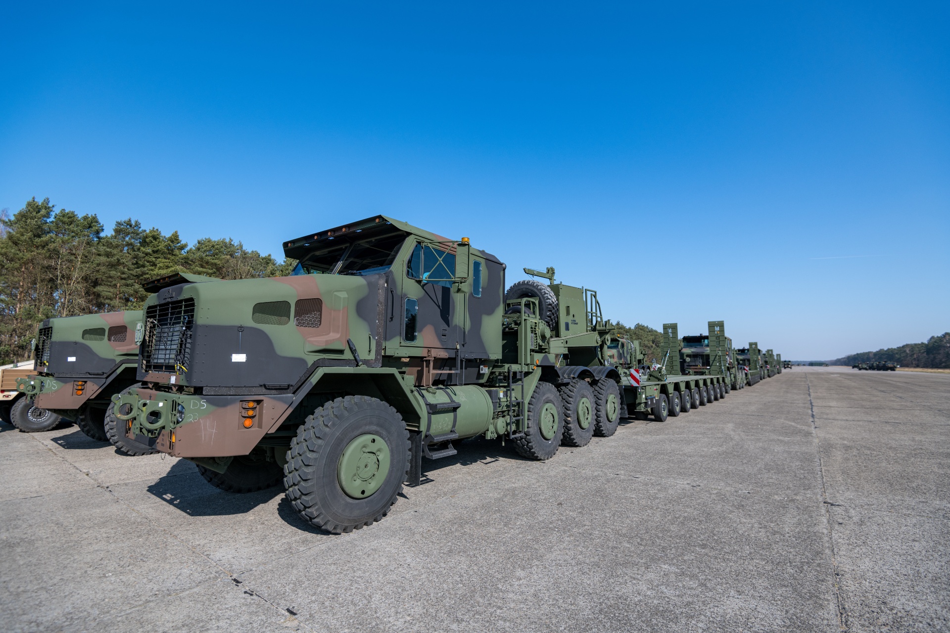 U.S. Army Enhanced Heavy Equipment Transporter Systems line up for a convoy, in a staging area of the Army Prepositioned Stock-2 site, in Zutendaal, Belgium, Mar. 09, 2022. Army Prepositioned Stocks is a U.S. Department of the Army program in which equipment sets are stored around the globe for use when a combatant commander requires additional capabilities. The U.S. Army has seven APS regions and APS-2 is designated for Europe. APS sites reduce deployment timelines, improve deterrence capabilities, and provide additional combat power for contingency operations. (U.S. Army photo by Pierre-Etienne Courtejoie)