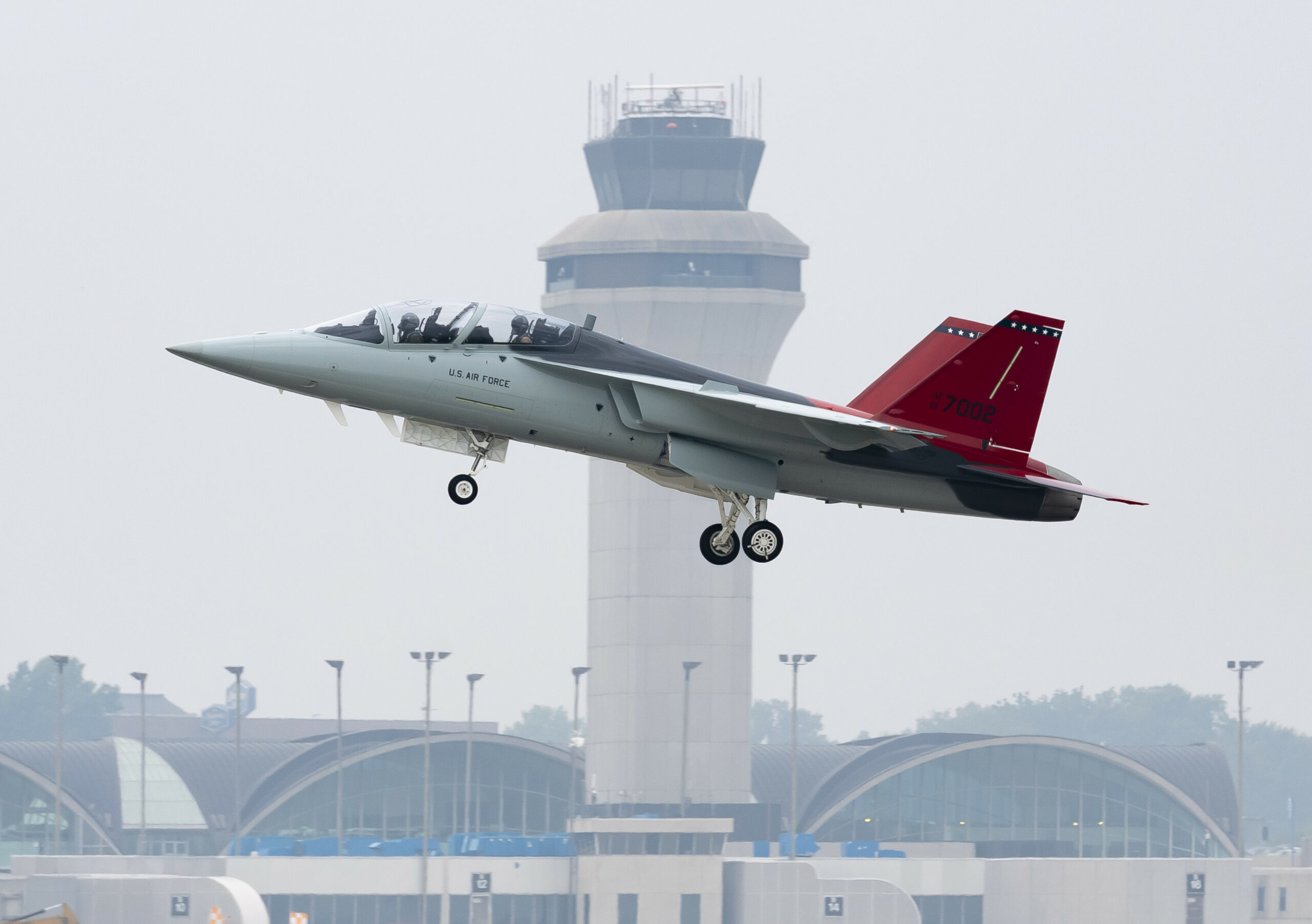A T-7A Red Hawk is seen taking off from an airport. The words 