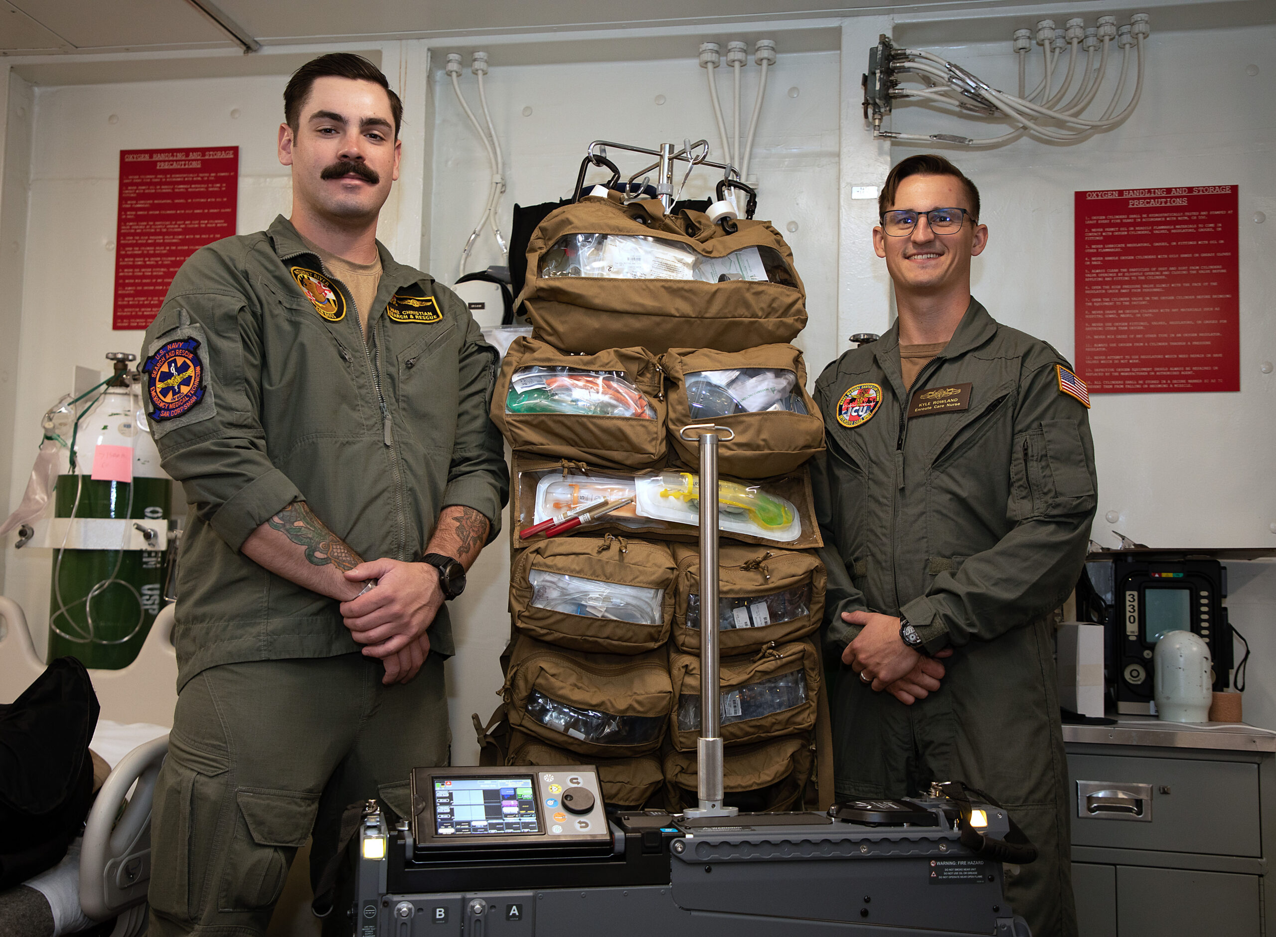 231011-N-MS174-1003 NORFOLK, Va. (Oct. 11, 2023) From left, Hospital Corpsman 2nd Class Bradley Christian, a search and rescue medical technician assigned to Navy Medicine Readiness and Training Command (NMRTC) Patuxent River, and Lt. Kyle Rowland, a critical care nurse assigned to NMRTC Camp Lejeune, pose for a photo with an integrated intensive care mobile unit in the medical department aboard Nimitz-class aircraft carrier USS Dwight D. Eisenhower (CVN 69). Christian and Rowland are a part of a 2-person team with the En-Route Care System (ERCS), one of the Navy’s newest medical capabilities that will deploy for the first time with the Eisenhower Carrier Strike Group to meet the demands of maritime operations in a distributed environment. (U.S. Navy photo by Bobbie A. Camp)