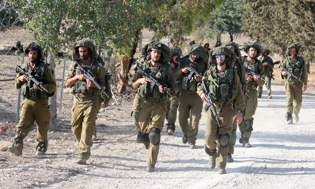 Israeli troops patrol at an undisclosed location along the border with the Gaza Strip