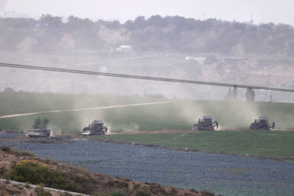 A picture taken from southern Israel along the border with the Gaza Strip shows Israeli army tanks and buldozers crossing the border into Gaza, on October 29, 2023