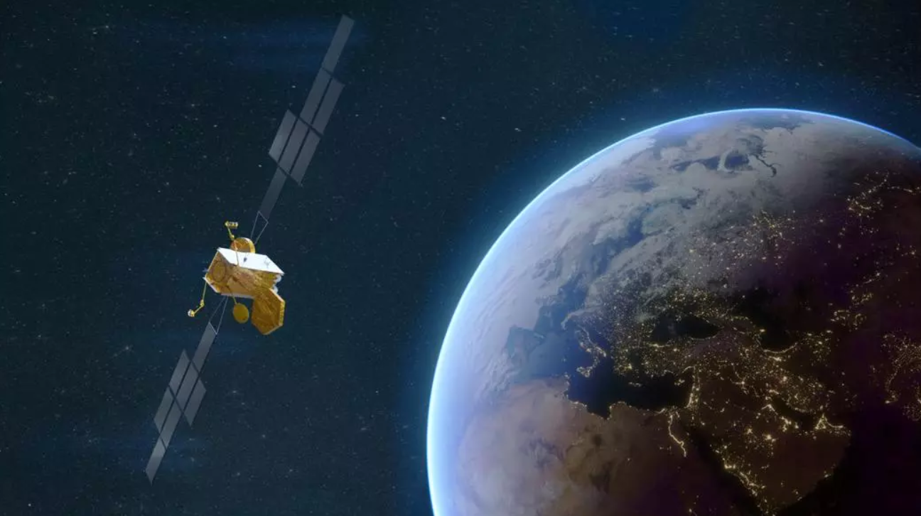 A rendering of a Skynet satellite in space. On the left, the satellite is seen hovering above Earth, which is seen on the right.