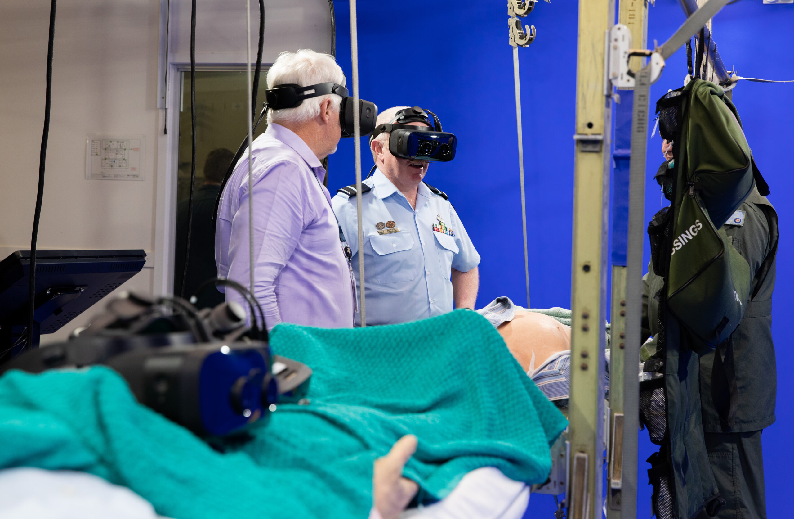 Commander Combat Support Group, Air Commodore Robert Graham (Centre) and Combat Support Group Sustainment Enterprise Manager, Brett Kleidon experience the new 'Blue Room' virtual trainer under the guidance of Flight Lieutenant Ben James (Right) at the Health Operational Conversion Unit RAAF Base Amberley, Queensland. *** Local Caption *** Commander Combat Support Group, Air Commodore Robert Graham, officially opened the Health Operational Conversion Units new Blue Room in October.The Blue Room is a mixed-reality simulator used to train Air Force medical staff in on board aircraft medical operations and emergency medical evacuation. The Blue Room is the first medical trainer of its kind in the ADF.
