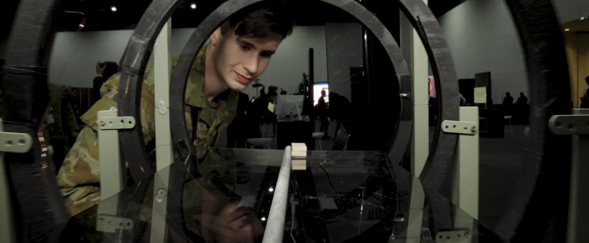 A uniformed personnel peeks inside a quantum tech display in a technology convention.