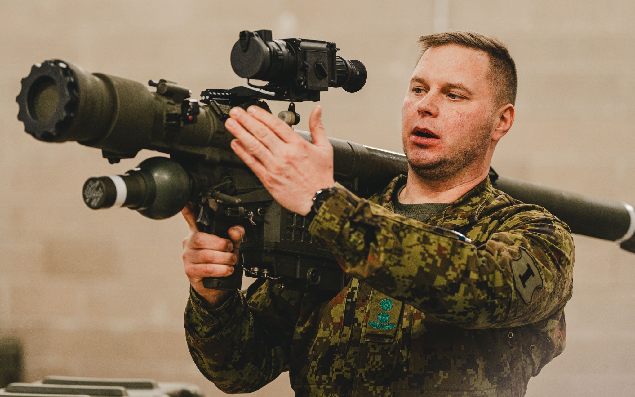 A soldier wearing a camouflaged uniform appears to be demonstrating how to carry the Piorun portable missile launching system. He has the equipment resting on his right shoulder, pointing it to the upper left side of the image.