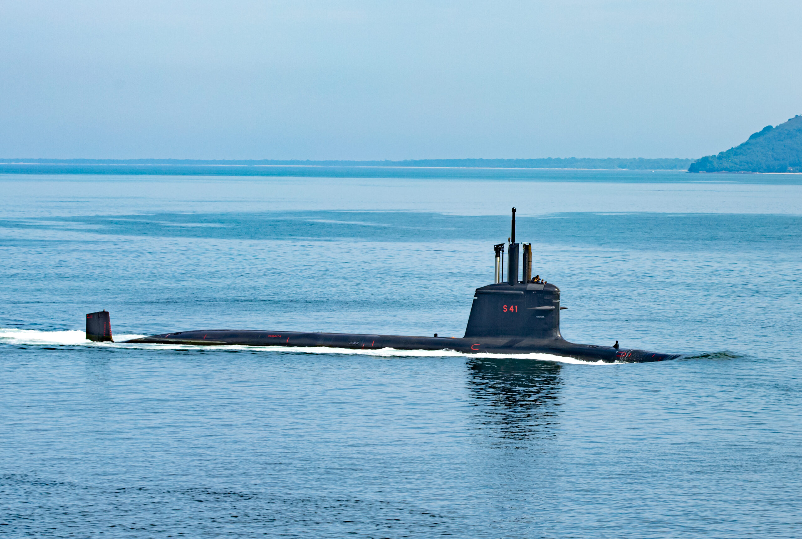 The black Humaitá (S-41) submarine is seen breaking the surface of the sea. Near the top of its hatch, 