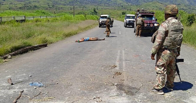 This handout picture released by the Royal Papua New Guinea Constabulary on February 19, 2024 shows a dead body on a road as officials patrol near the town of Wabag