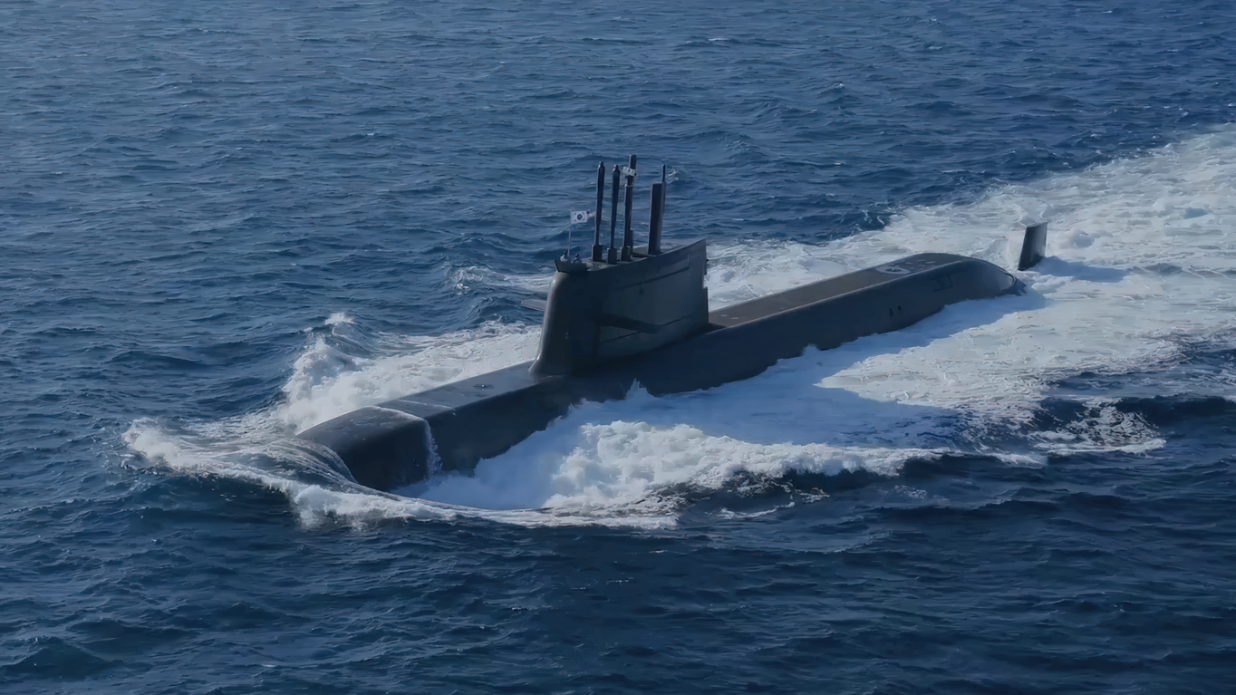 ROKS Dosan Ahn Changho (SS-083), a Jangbogo-III class submarine, is seen floating half-submerged in deep blue waters. The ship is painted black. A South Korean flag is seen hoisted up on a pole on top of the submarine's sail.