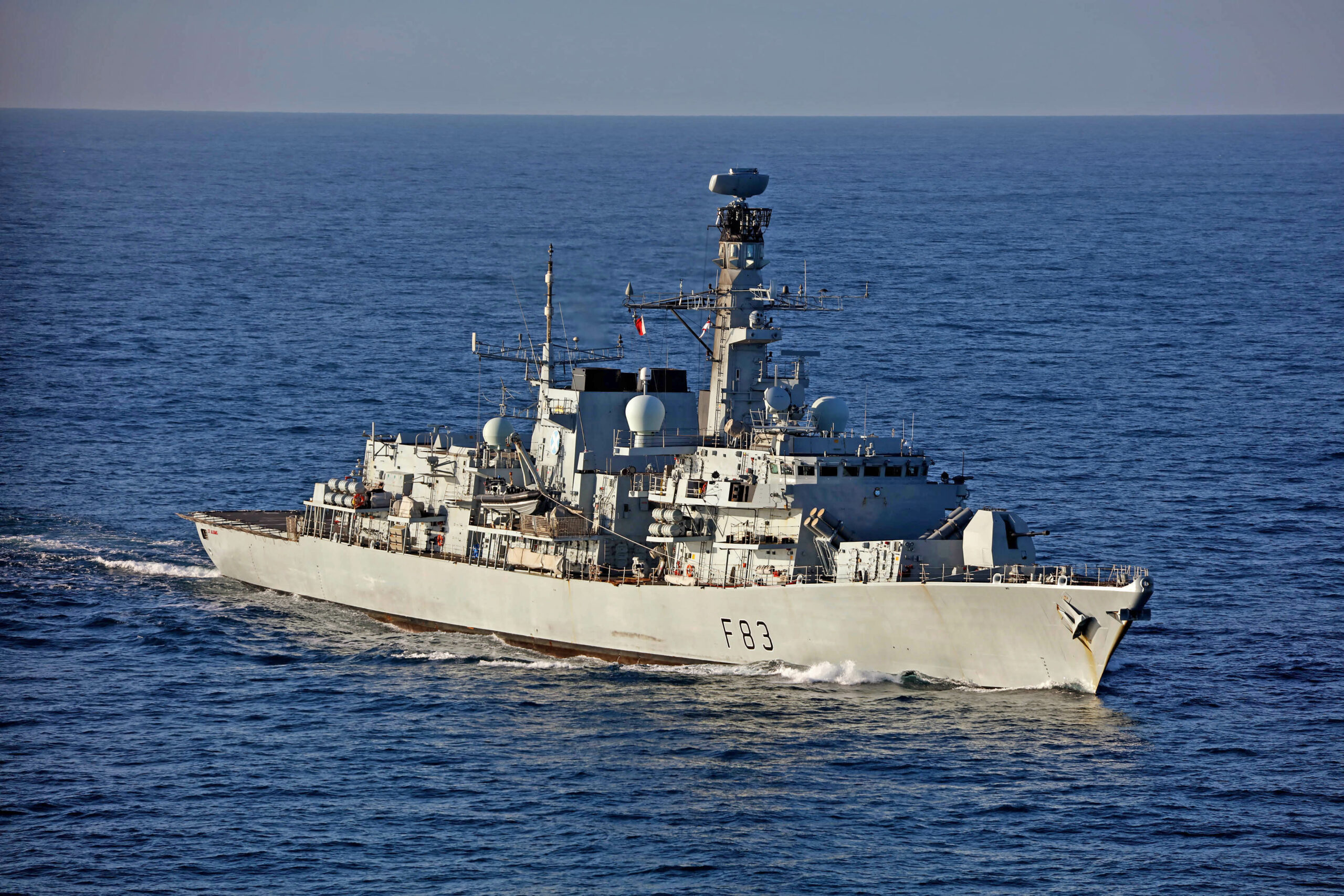The UK Royal Navy's HMS St Albans frigate is seen sailing in calm, deep blue waters. The ship is painted gray, with 
