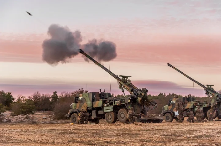 A Nexter CAESAR self-propelled howitzer is seen firing a 155mm artillery shell. The howitzer system is installed in the back of a 6x6 truck body.