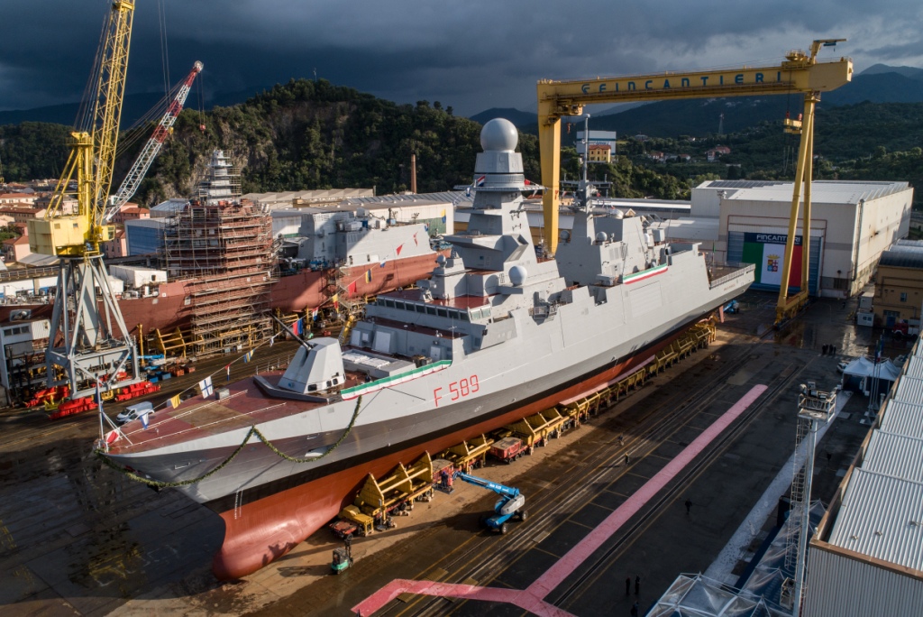 An image of the Italian Navy FREMM frigate, Emilio Bianchi, at the Riva Trigoso integrated shipyard. The ship, painted gray, is decorated with ribbons of laurels on the railings of its deck. It has 